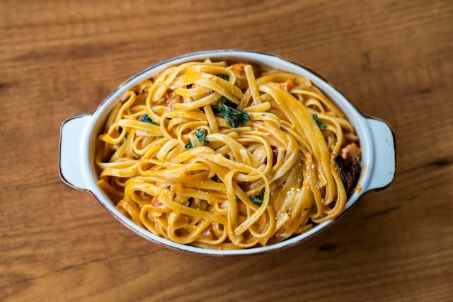A creamy plate of butter chicken linguine pasta garnished with fresh herbs.