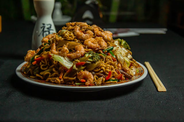 A plate of steak and shrimp stir-fry with broccoli and noodles, featuring vibrant and delicious presentations.